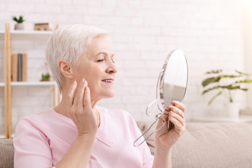 Woman admires her face in mirror after skin cancer scare